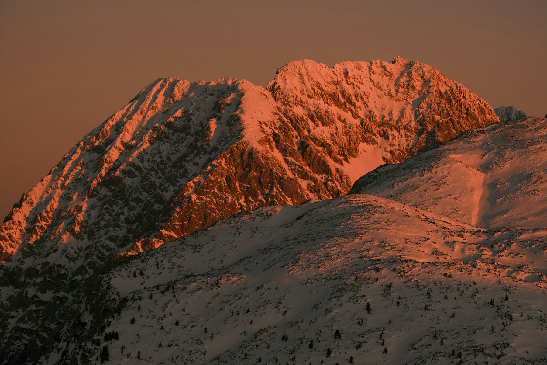 A mountain face glowing orange in late alpenglow light