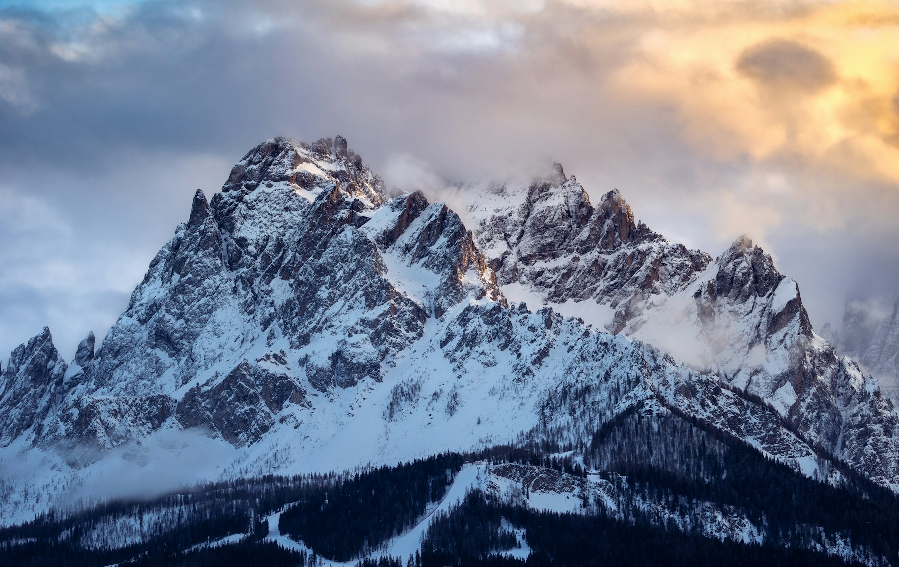A dramatic snow-covered mountain summit under warm morning cloud