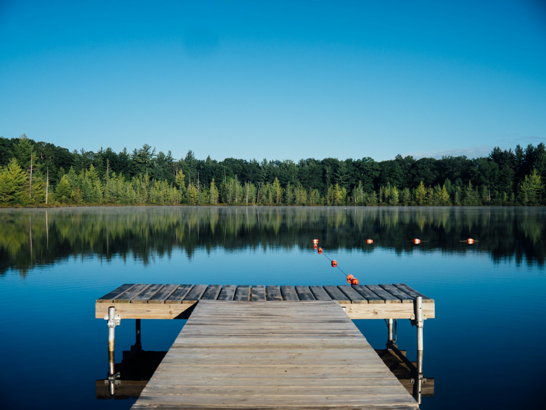 A lone dock reaching into a calm lake at dusk