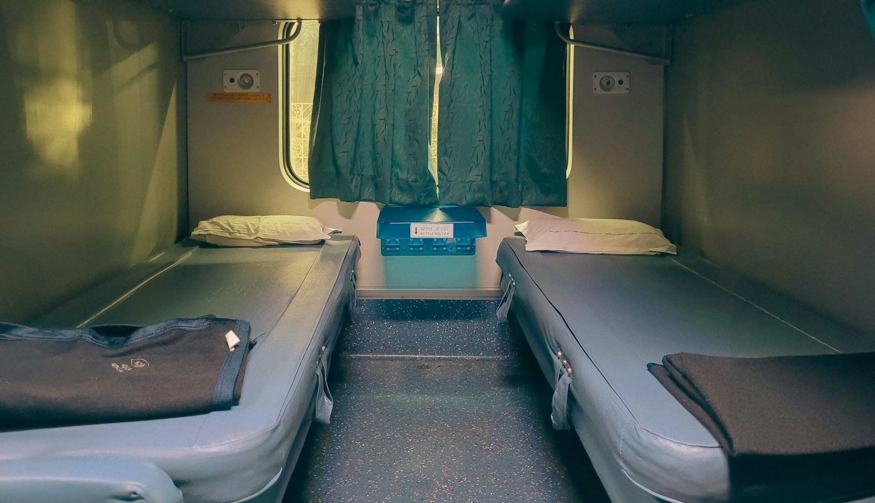A sleeper cabin with two made beds and a drawn curtain