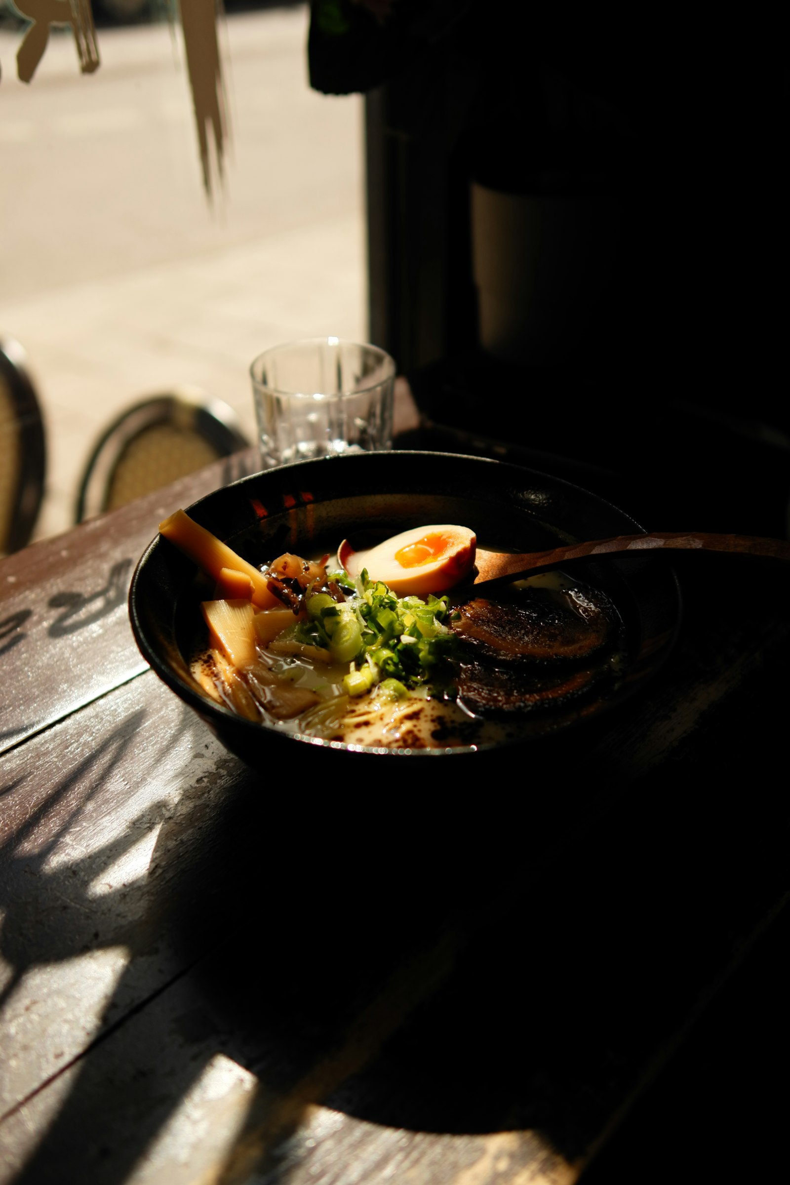A dark counter with a ramen bowl in dramatic side light